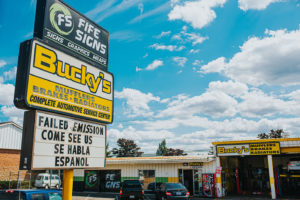 Car being repaired at Bucky's Fife Auto Repair next to colorful billboard
