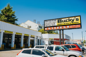 Cars being repaired at Bucky's Shoreline Auto repair location next to billboard